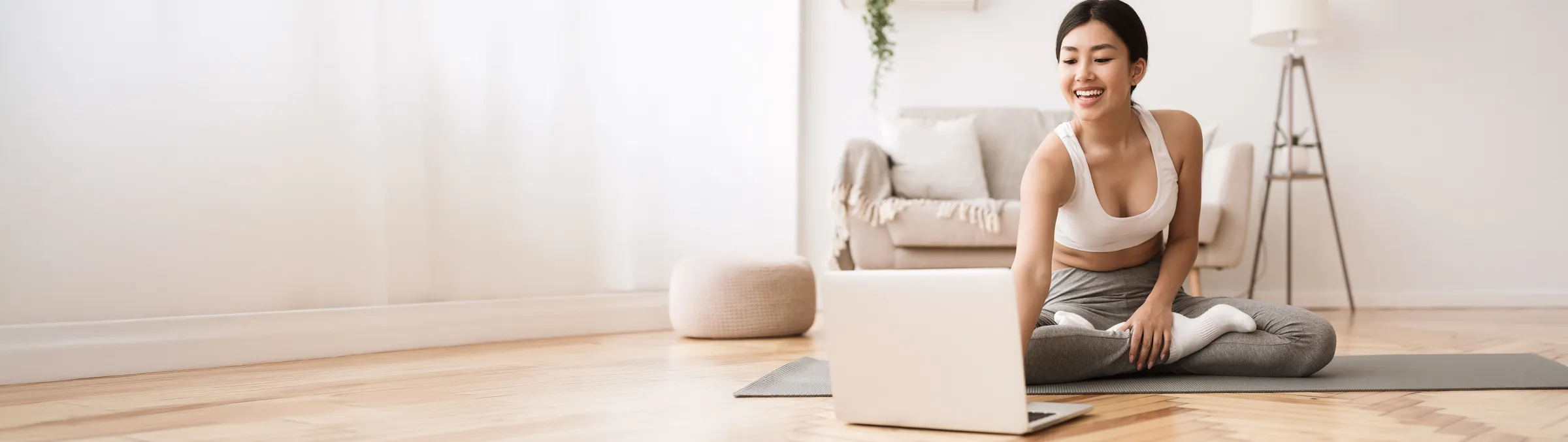 A woman following a guided workout at home with her laptop